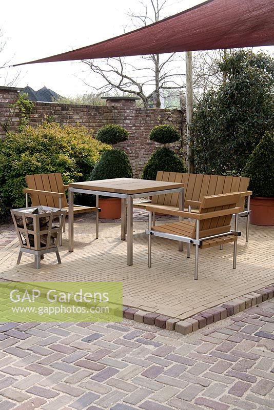 Log fire and wooden furniture on patio with canvas canopy - Appeltern garden, Holland 