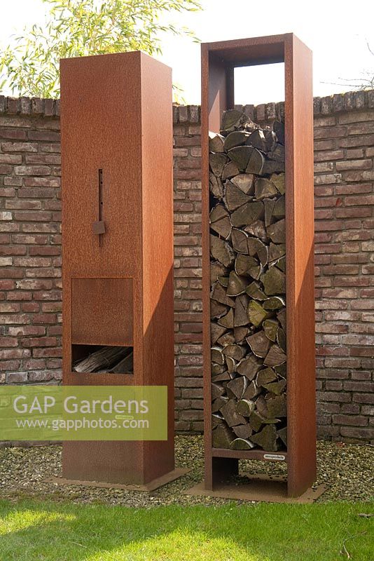 Rusted metal log burning patio heater and wood storage - Appeltern garden, Holland 
