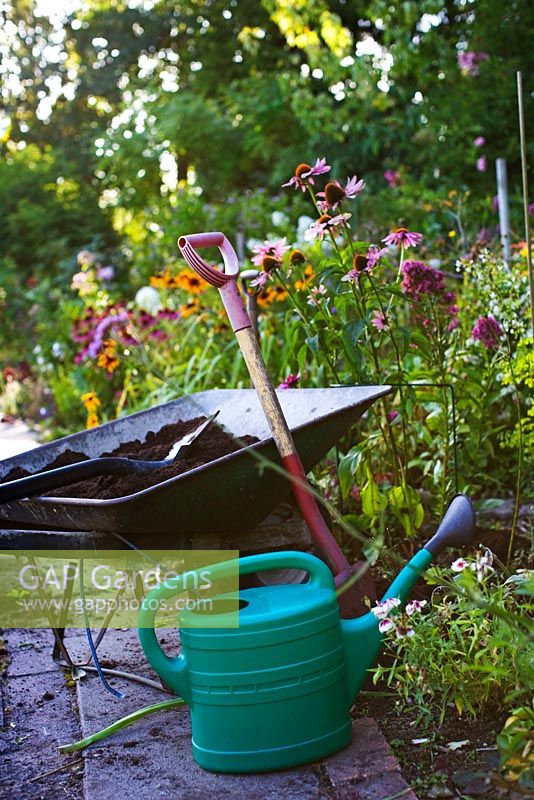 Replacing plants, organic compost in wheelbarrow, spade and watering can