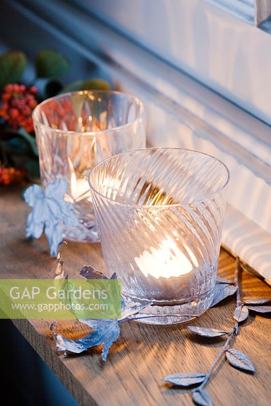 Silver sprayed leaves used as a festive decoration with a vintage glass tealight holder