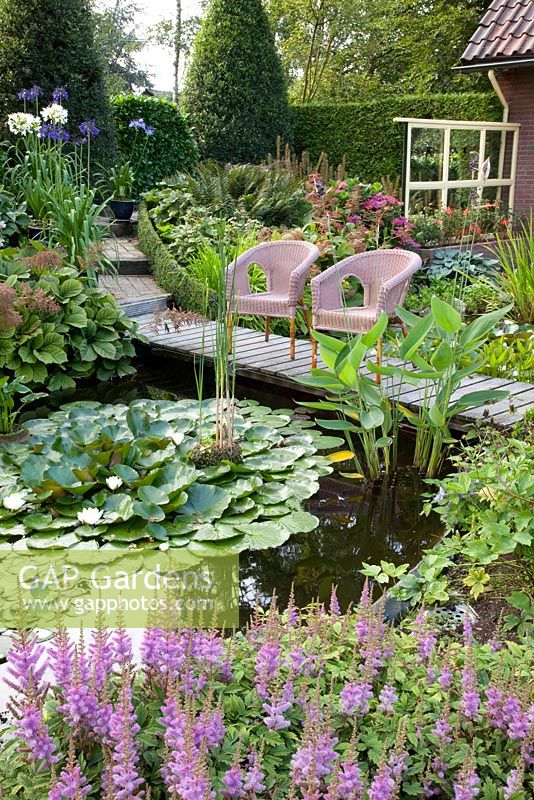 Pond with seating area, Astilbe chinensis 'Pumila' in foreground 