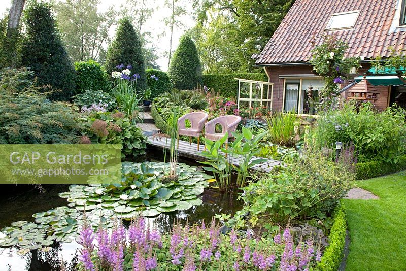 Pond with seating area, Astilbe chinensis 'Pumila' in foreground 
