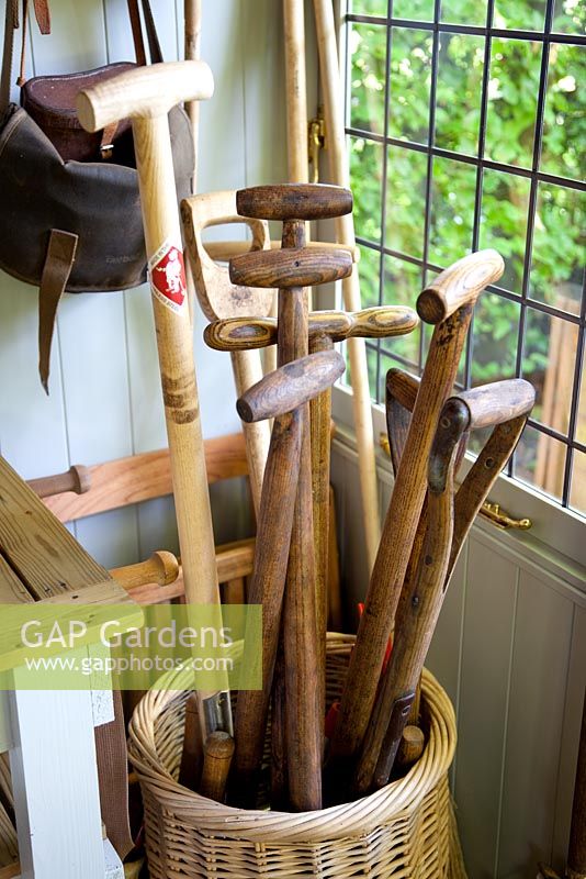 Wooden handled gardening tools in wicker basket