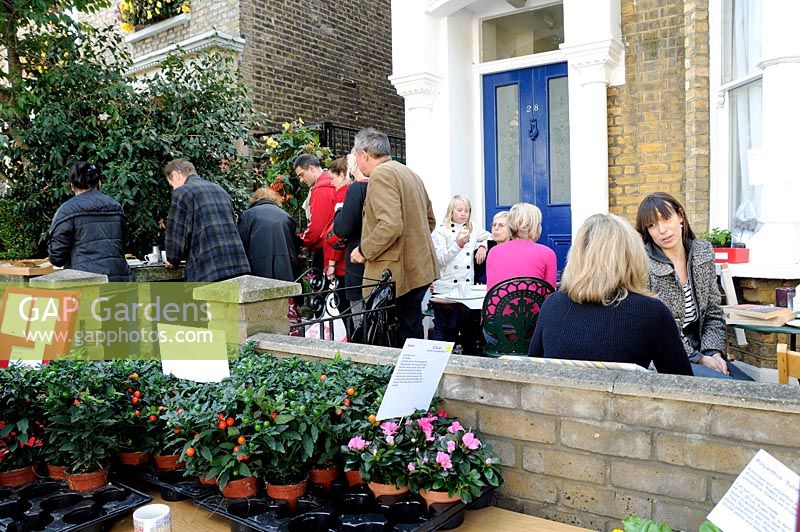 People having tea in a front garden at a plant sale, Hackney, London 