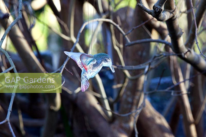 A glass bird hangs from a tree.  The Old Malthouse