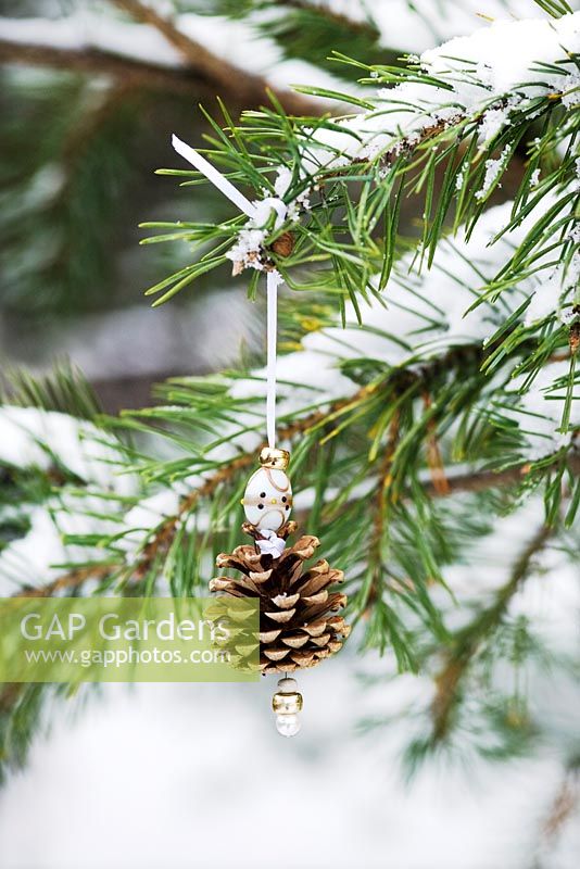 Making pine cone decorations with beads - Finished decoration hanging in a snow covered conifer tree.