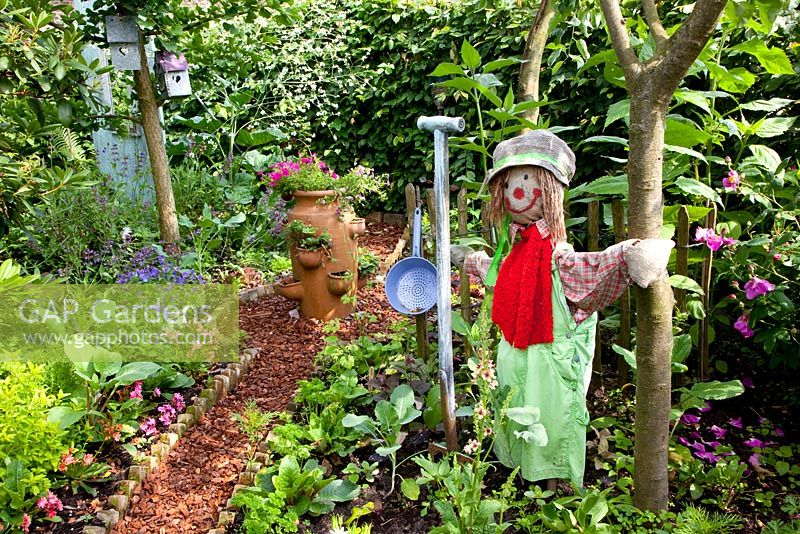 Vegetable garden for children with scarecrow and bark chipping path
