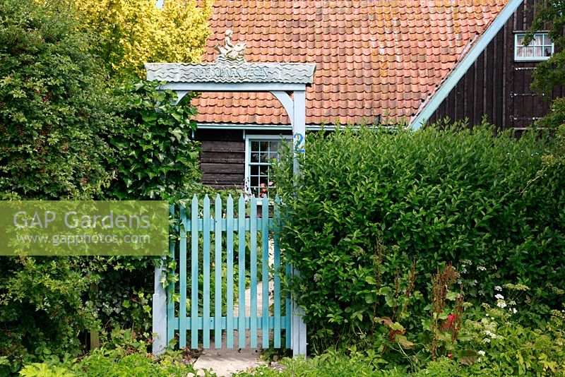 Gate with ceramics at the entrance of the garden. Sign with the words 'Op Hoop van Zegen' typical dutch expression - The garden of sculptor Mieke Holt at Wieringen, Holland 
