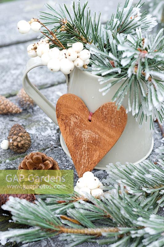 Symphorcarpos albus - Frosted snowberries and pine foliage in a jug with wooden heart and cones