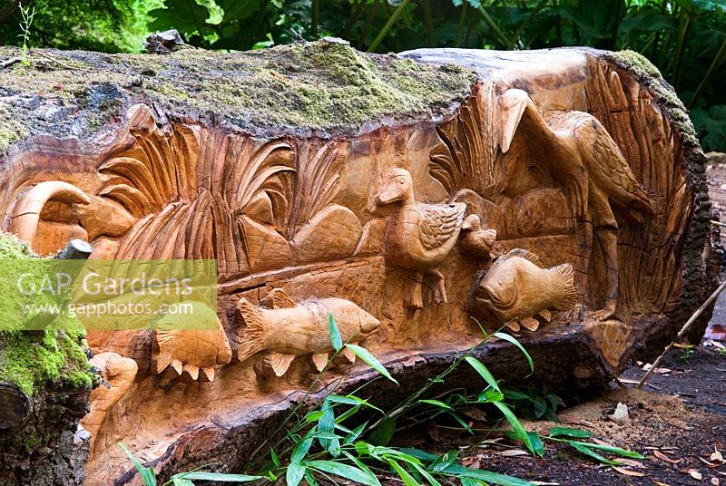 Felled Oak carved with seats and scenes of birds, fish and animals by chainsaw sculptor Matthew Crabb. Abbotsbury Subtropical Gardens, Dorset, UK
