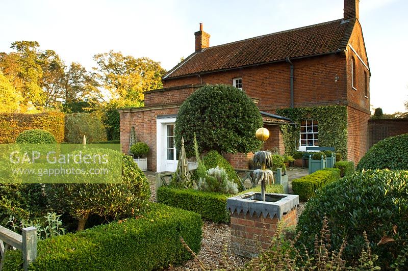 Classic country garden with gravel path, water feature and hedging. Silverstone Farm, Norfolk