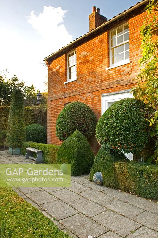 Formal Buxus topiary spheres and pyramids at front of house. Silverstone Farm, Norfolk
