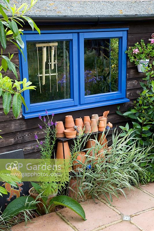 Potting shed with collection of terracotta pots on wrought iron shelves