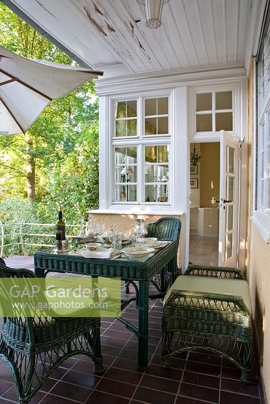 Wicker furniture and a table prepared for dinner on the terrace of a Berlin villa