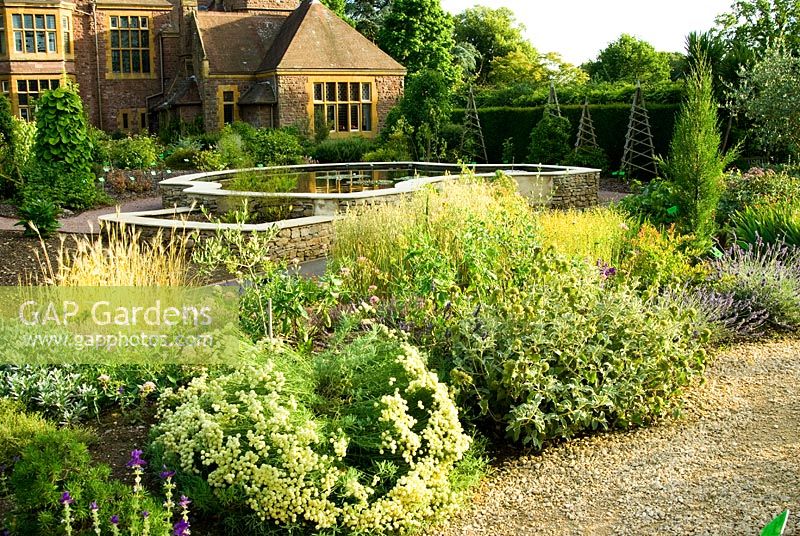 View across raised pool to The Holmes from the raised, free draining bank of the Mediterranean Climates Collection planted with Santolina, Phlomis and Lavandula. University of Bristol Botanic Garden, Bristol, UK