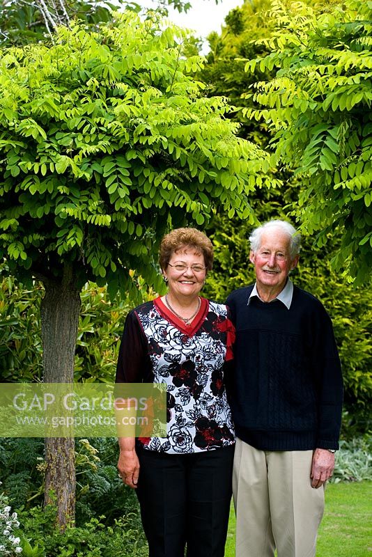 Sandra Muckle and her husband Ivan at Millisle garden, in front of mop-top Robinias