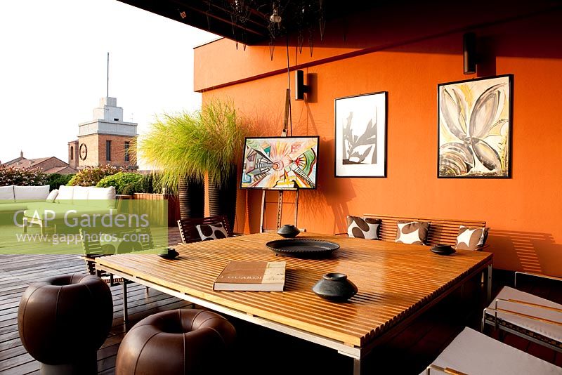 Terrace with contemporary seating area with sofas and orange painted walls in Ferrara, Italy