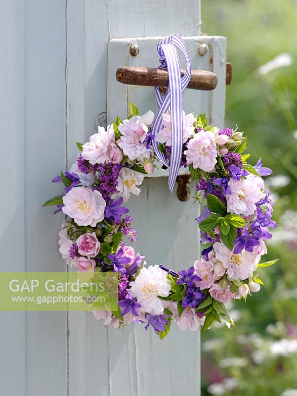 Hanging wreath with Roses, Campanulas, Thyme, and mint tied with ribbon on door
