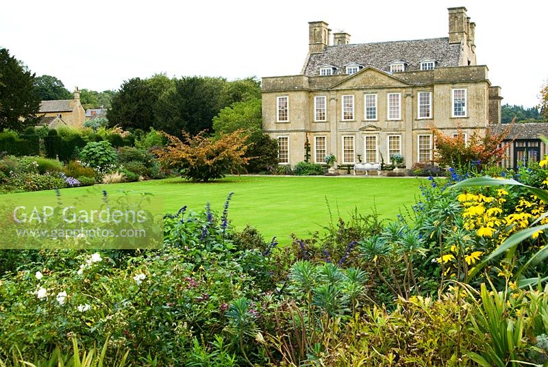 Bourton House, dating from the early eighteenth century, set off by a pair of Parrotia persica trees and a broad sweep of lawn. Bourton House, Bourton-on-the-Hill, Moreton-in-Marsh, Glos, UK
