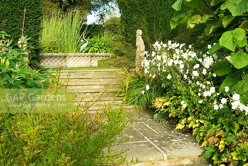 Steps edged with white flowered Japanese Anemones lead up to basket pond from 1851 Great Exhibition. Bourton House, Bourton-on-the-Hill, Moreton-in-Marsh, Glos, UK