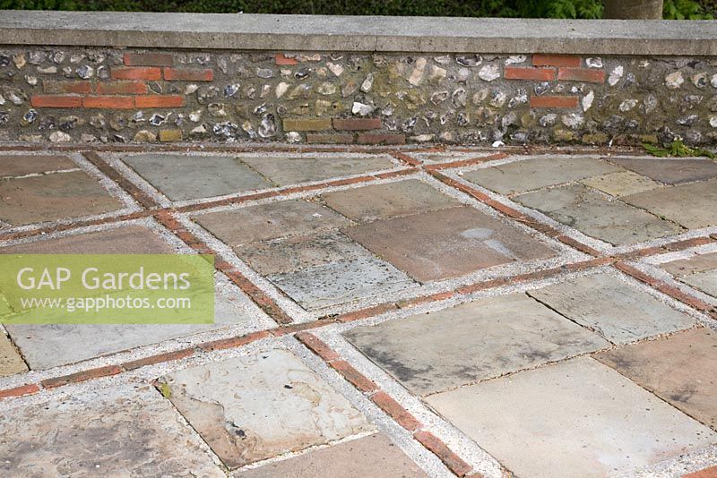 Paving of old slabs with bricks and walling of flint and brick. West Dean Gardens