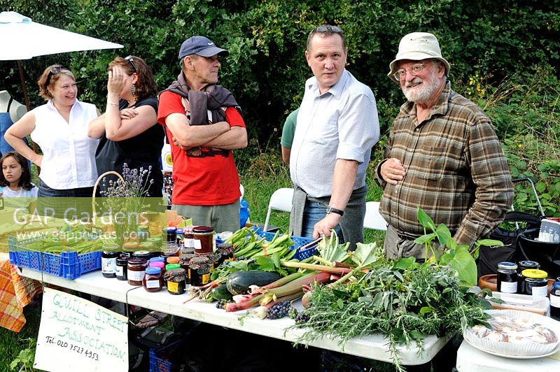 People behind allotment stall at festival selling herbs, vegetables and other produce Highbury, London Borough of Islington.