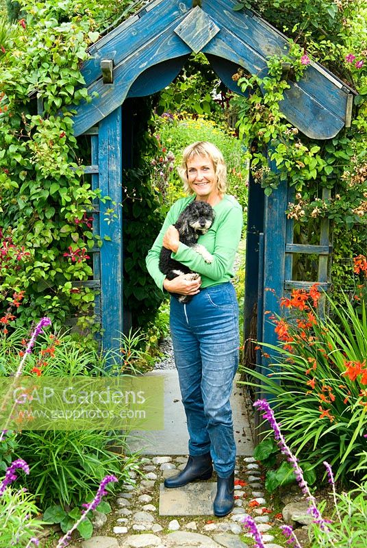 Tina Primmer with her miniature poodle. Poppy Cottage Garden, Roseland Peninsula, Cornwall, UK