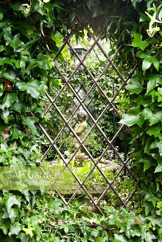 Hedera - Ivy surrounds view into the Secret Garden with water feature in centre. The Secret Garden at Serles House, Wimborne, Dorset, UK