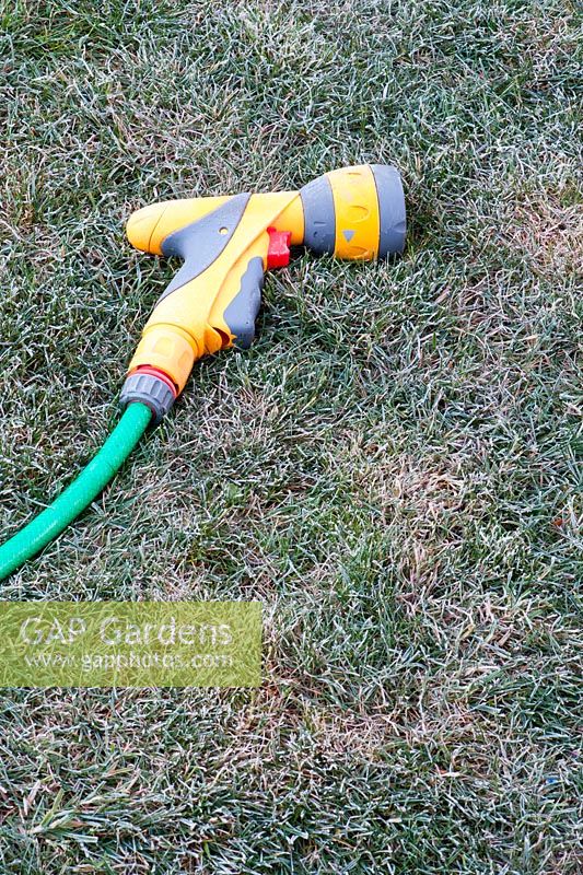Garden hose nozzle on a frosty lawn