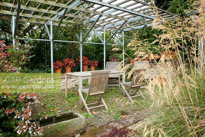 Table and chairs in patio area - Derry Watkins Garden at Special Plants, Bath, UK