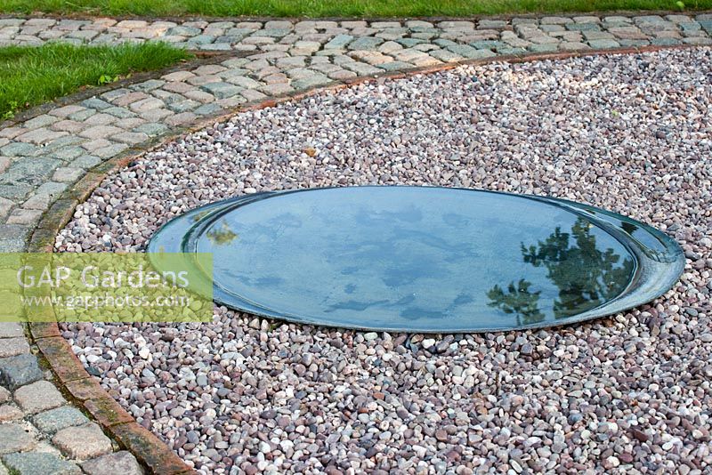 Circular shallow pond surrounded by gravel surface - The Corner House, Wiltshire.