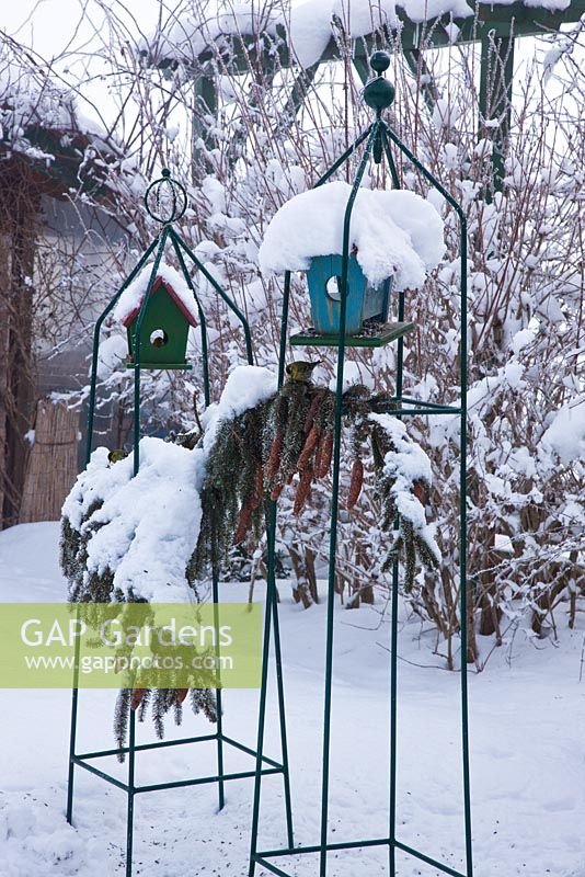Wooden bird boxes in metal frames covered with snow