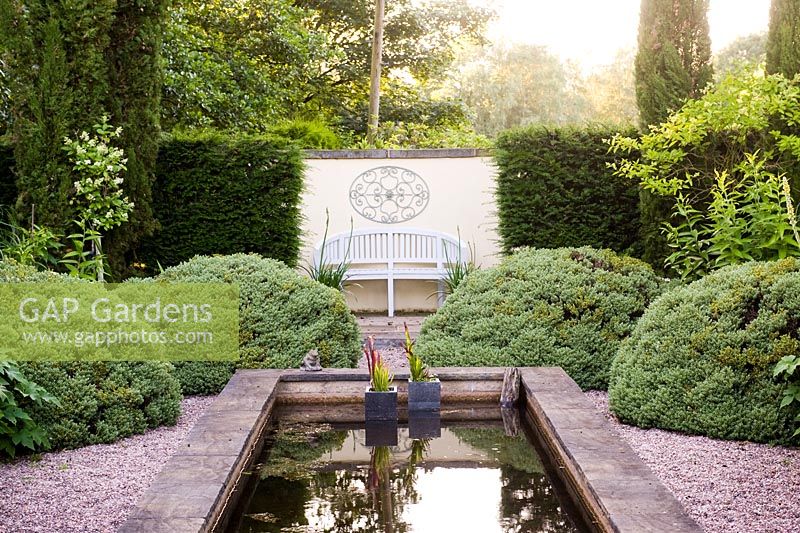 Looking south in the 'Italian Garden' with reflecting pool and green and white planting. Structure provided by Taxus - Yew hedges, Cupressus sempervirens, Hebe sutherlandii and standard Ligustrum delavayanum - Greenways garden, Cheshire
