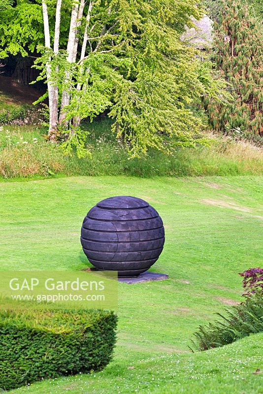 Dartington Hall, Devon. Historic Garden Grade II. July. 'Black Sphere' by David Nash - on loan from Yorkshire Sculpture Park.(Below the Tiltyard)