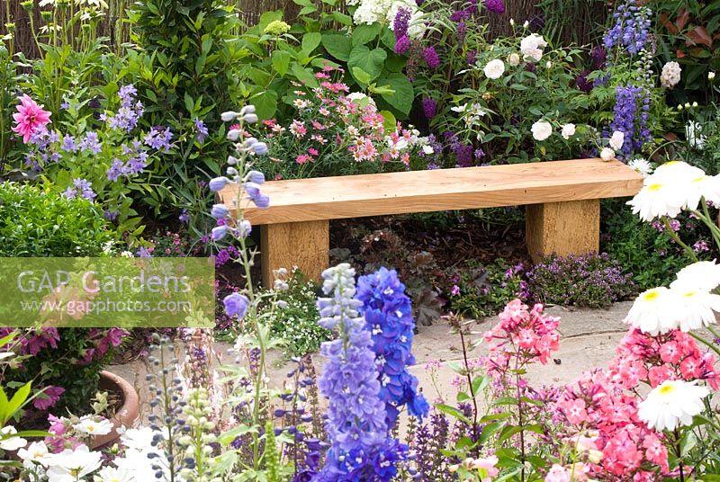 Colourful cottage garden with wooden bench. The Christie Charitable Fund 'The Cottage Door' garden designed by Andy Walker (Walker Landscape Design and Consultancy). RHS Tatton Flower Show 2011