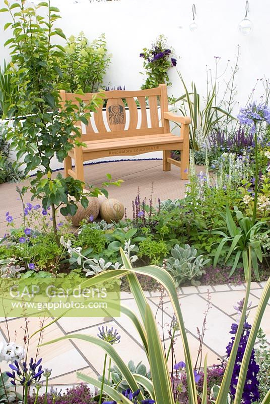 Green, white and blue beds, paths and wooden bench on patio. Respiratory Education UK  'A Breath of Fresh Air' garden designed by Sally Parkinson at Gardens and Spaces. RHS Tatton Flower Show 2011