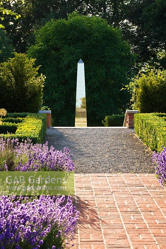 Garden with red brick Lavandula - Lavender, edged path leading to metal sculpture, Oxfordshire 
