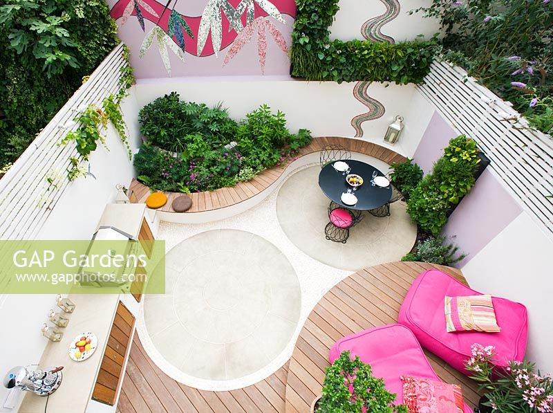 Elevated view of small patio garden with decking, pink chairs, mosaic by Celia Gregory, London.