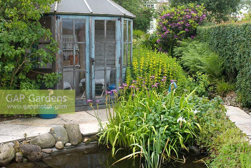 Wooden hexagonal summer house in cottage garden with pond 
