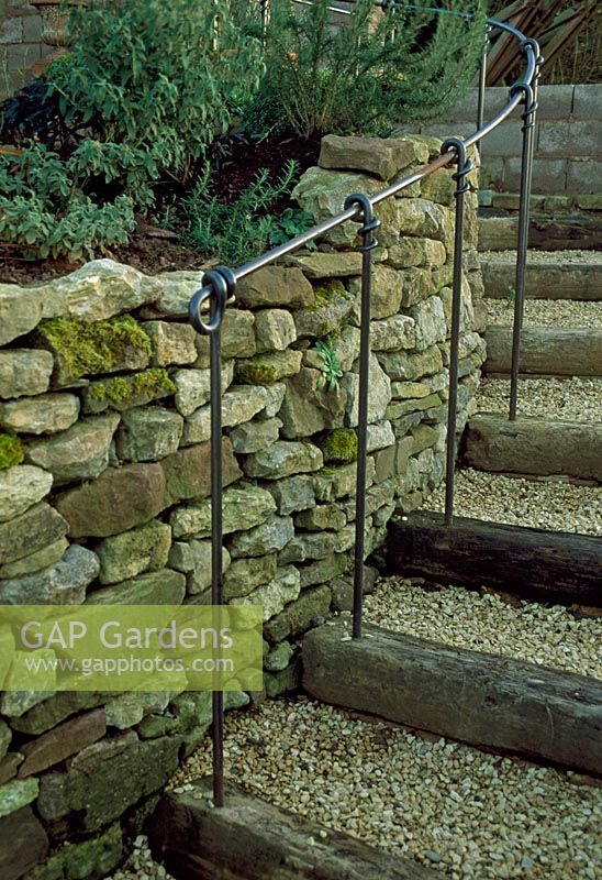  A set of garden steps created using railway sleepers, gravel, dry stone wall and iron handrail 