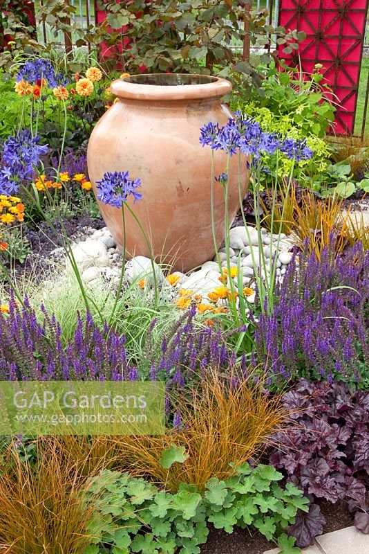 Ornamental terracotta urns in centre of mixed summer borders 