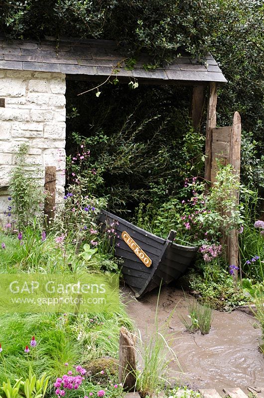 Wooden boat used as planter in rustic outbuilding 