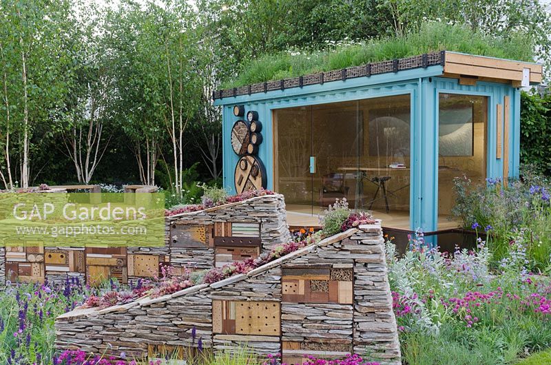 Modern summerhouse in garden with dry stone walls and insect habitats 