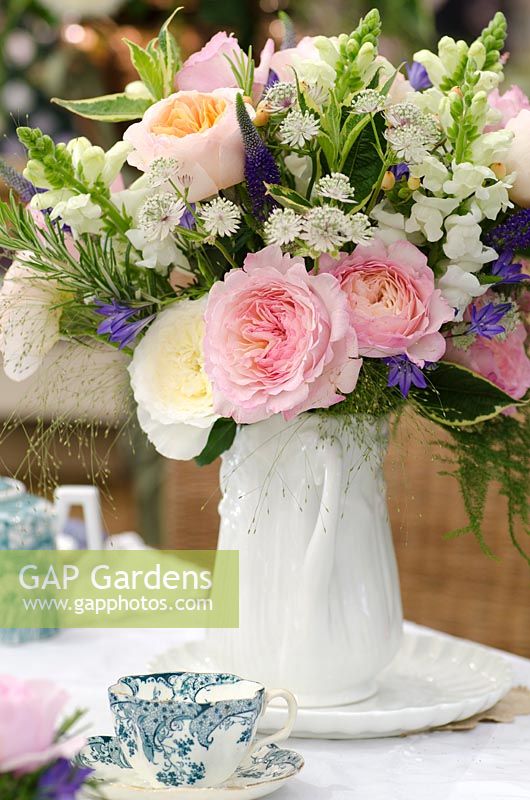 Flower arrangement in white ceramic jug, flowers include pink and white Rosa, Astrantia, Antirrhinum and Veronicastrum