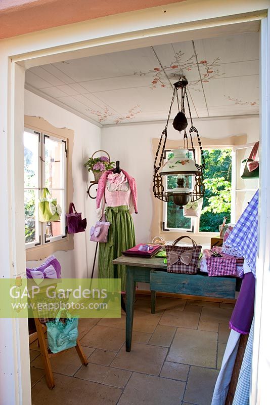 A typical Bavarian dress, the Dirndl, and handbag display in the traditional summer house with a glass and iron lamp - Handbag Garden, Freising, Germany 
 