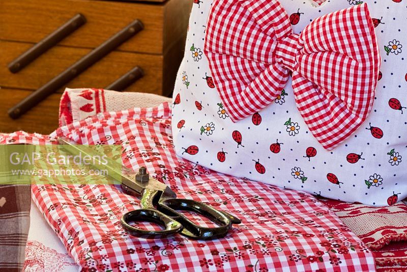 A pair of scissors and a chequered bow on red and white fabrics - Handbag Garden, Freising, Germany 