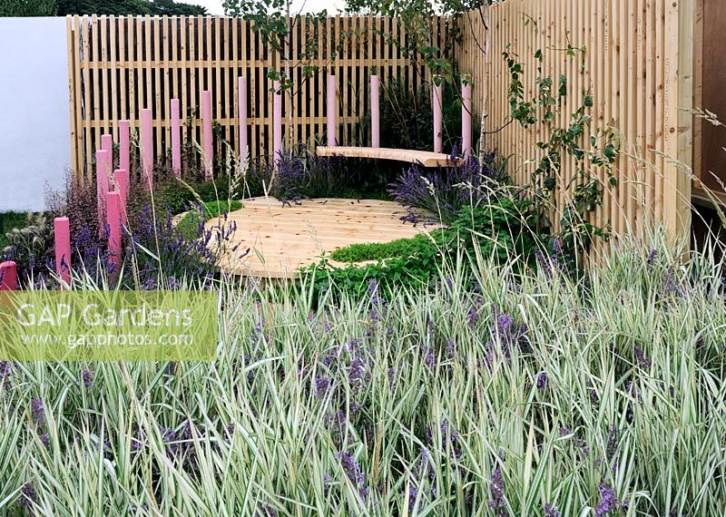 Garden planted with swathes of Phalaris arundinacea 'Feesey', and Nepeta 'Six Hills Giant'. Raised seating area with pink timber posts surround - RHS Tatton Park Flower Show 2011 
