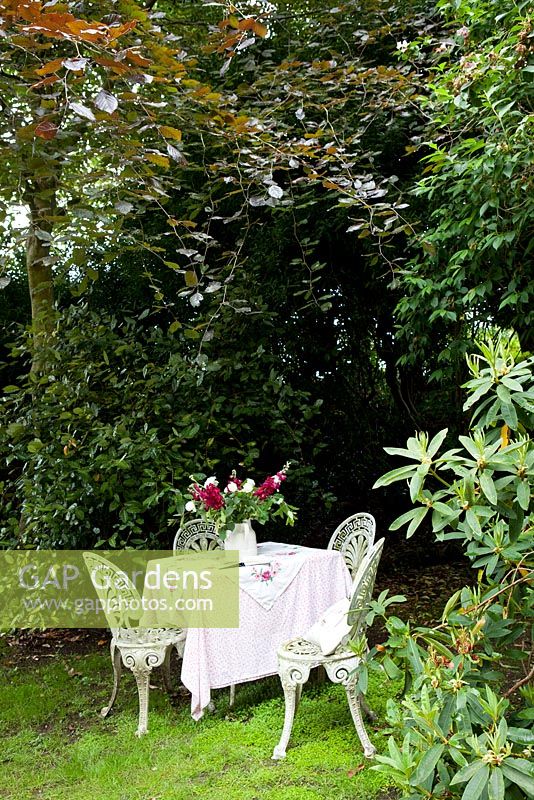White metal chairs and table in shady garden