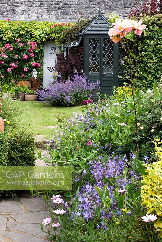Steps leading to a lawn with summerhouse in a cottage garden - Dunromin, Somerset