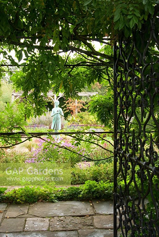 View into the Formal Garden through the gate with statue of girl holding the lamp of wisdom by Nathan David 